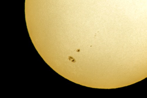 Close-up of the sun showing sunspots against a bright yellow surface.