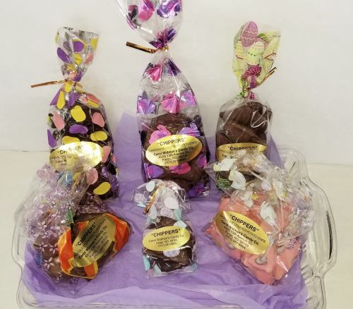 A variety of colorful, wrapped chocolate treats displayed on a tray with decorative packaging and labels.