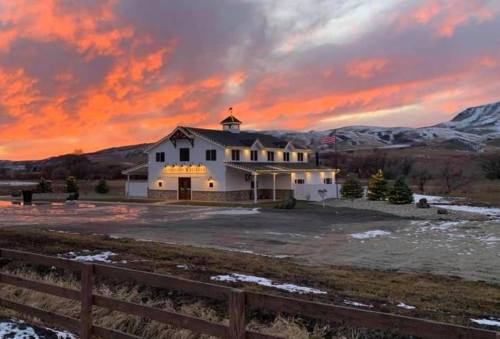 A white building with festive lights against a vibrant sunset, surrounded by snow and mountains in the background.