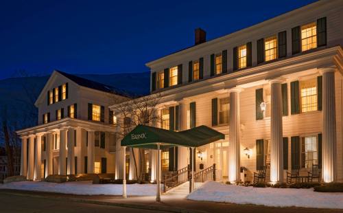 A charming historic hotel illuminated at night, featuring white siding, green awnings, and classic architectural details.