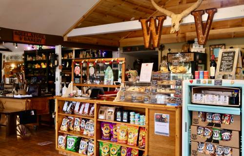 Cozy bakery interior with wooden counters, snacks on display, and rustic decor featuring a deer antler.