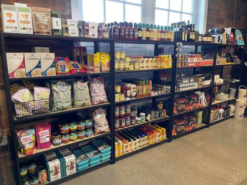 A well-stocked shelf displaying various food products, including sauces, snacks, and condiments in jars and boxes.