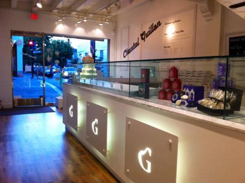 A modern dessert shop interior with a glass display case, showcasing pastries and treats, and a welcoming entrance.