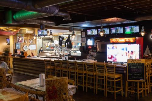 A cozy restaurant interior featuring a bar, multiple TVs, and wooden seating, with a chalkboard menu highlighting crawfish.