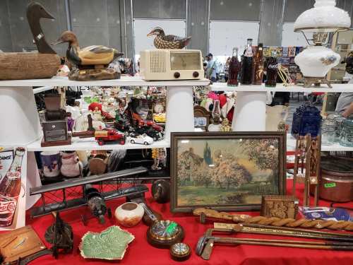 A display of various antiques and collectibles, including figurines, a vintage radio, and decorative items on shelves.