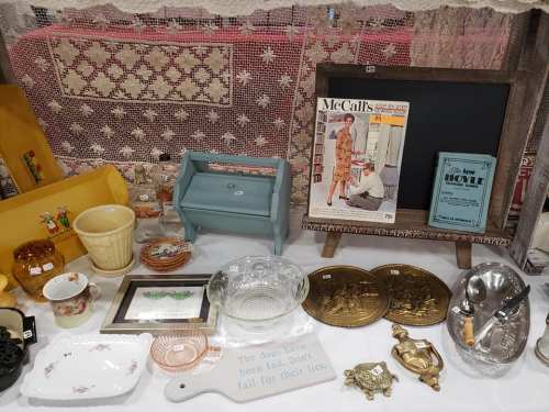A display of vintage items including dishes, a magazine, and decorative pieces on a table.