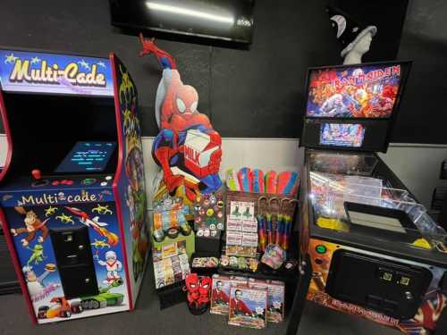 A colorful arcade setup featuring a Multi-Cade machine, Spider-Man decor, and various gaming merchandise.