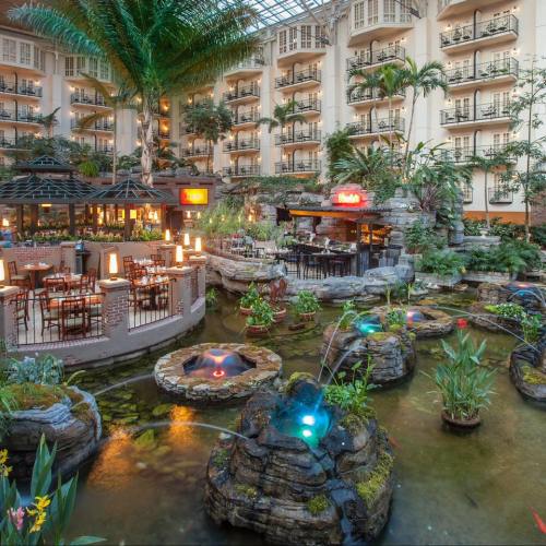 Lush indoor garden with water features, seating areas, and tropical plants in a spacious atrium.