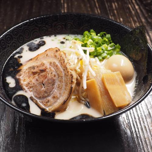 A bowl of ramen with sliced pork, soft-boiled egg, bamboo shoots, green onions, and seaweed in a creamy broth.