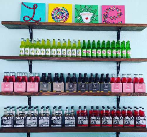 Colorful shelves display various soda bottles, with vibrant artwork spelling "L O V E" above them.