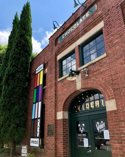 Exterior of a brick building with "Chocolate" sign, colorful pride flag, and Black Lives Matter signs.
