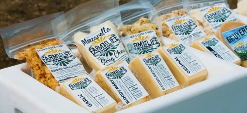 A display of various cheese products in clear packaging, labeled with flavors like Garlic, Original, and Bloody Mary.