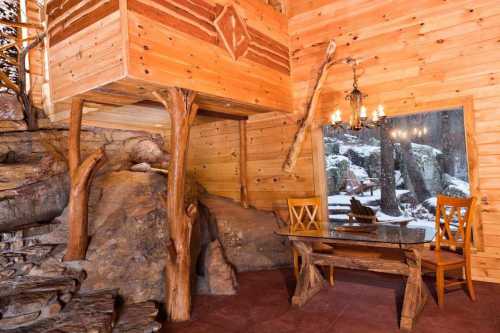 Cozy wooden interior featuring a rustic table and chairs, with a view of snow-covered trees outside.