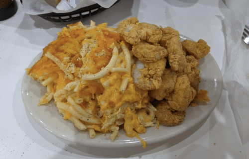 A plate of macaroni and cheese alongside crispy fried chicken pieces.