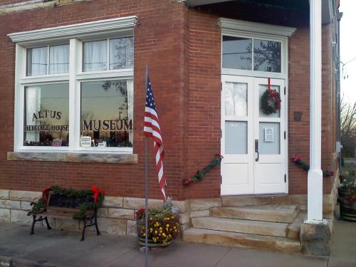 Exterior of the Altus Heritage House Museum, featuring a brick facade, festive decorations, and an American flag.