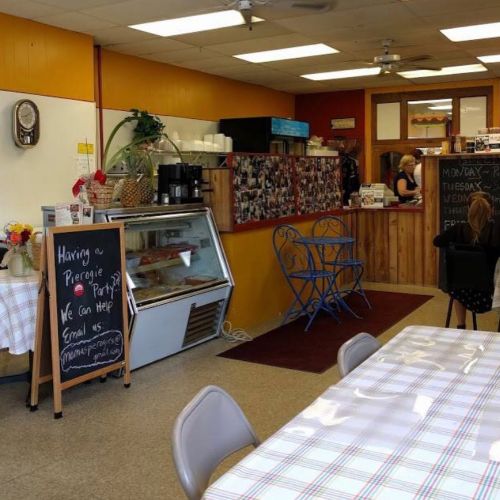Cozy café interior with a display case, chalkboard sign, and seating area, featuring warm colors and a welcoming atmosphere.