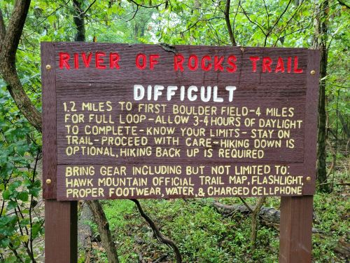 Sign for River of Rocks Trail, listing difficulty, distance, and safety tips for hikers, including gear recommendations.