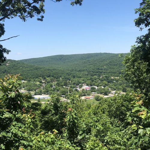A scenic view of a green valley with a small town nestled among the hills under a clear blue sky.