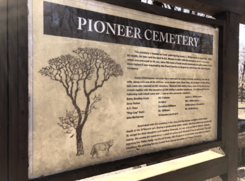 Sign for Pioneer Cemetery, detailing its history and notable individuals buried there, with a tree illustration.