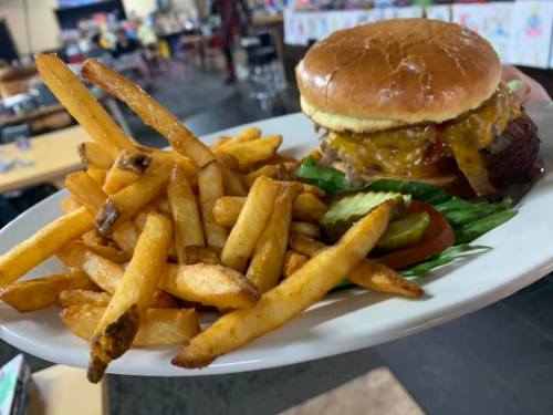 A plate with a cheeseburger topped with melted cheese, served with a side of golden French fries and pickles.