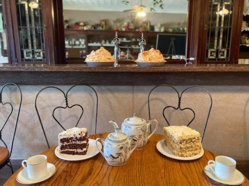 A cozy café scene with two cakes on display and a table set with teapots and cups.