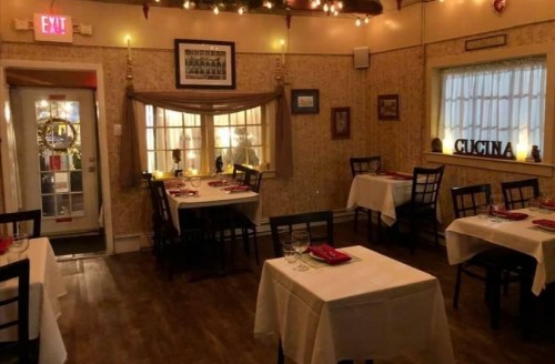 Cozy restaurant interior with white tablecloths, dim lighting, and decorative walls, creating an inviting atmosphere.