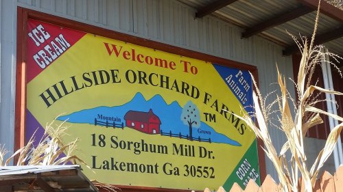 Bright sign welcoming visitors to Hillside Orchard Farms, featuring ice cream and farm-themed graphics. Located in Lakemont, GA.