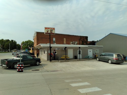 A small diner named Misty's, with outdoor seating, surrounded by buildings and parked cars on a quiet street.