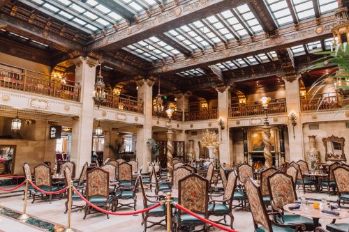 Elegant hotel lobby with ornate decor, plush seating, and a glass ceiling, creating a luxurious atmosphere.
