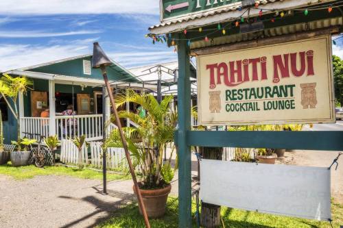 Sign for Tahiti Nui Restaurant and Cocktail Lounge, surrounded by tropical plants and a vibrant outdoor setting.