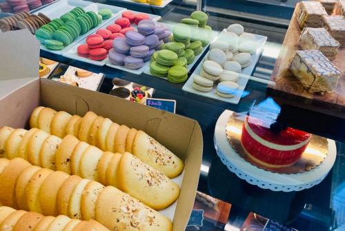 A display of assorted pastries, including macarons, cookies, and a red velvet cake in a bakery setting.