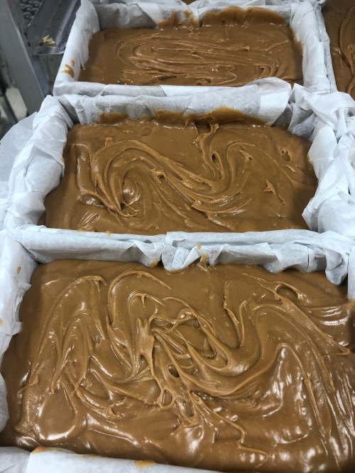 Three trays lined with parchment paper filled with smooth, swirled caramel or fudge mixture.