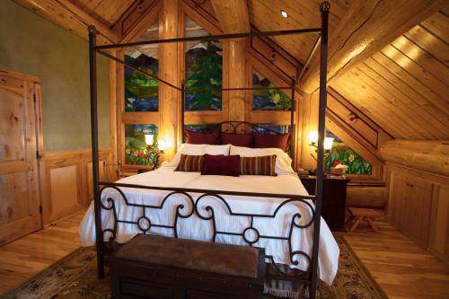 Cozy bedroom with a four-poster bed, wooden walls, and colorful stained glass windows. Warm and inviting atmosphere.