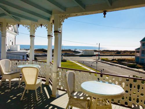 A sunny balcony with white wicker furniture overlooks a beach and ocean view.