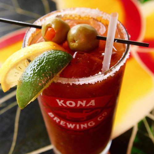 A close-up of a cocktail garnished with olives, lemon, and lime, served in a glass with a salt rim.
