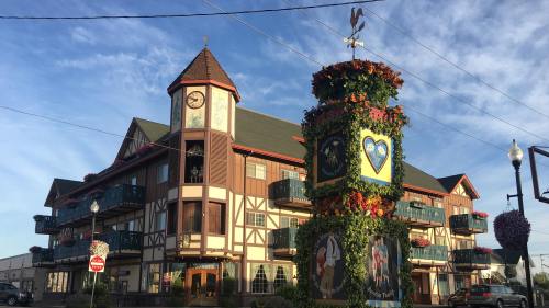 A charming building with a clock tower and colorful flower displays, set against a blue sky.