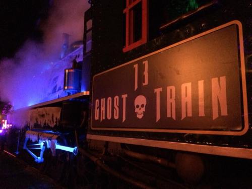 A spooky train with a sign reading "Ghost Train 13," surrounded by colorful lights and fog.
