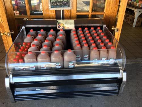 A display case filled with bottles of chocolate milk, neatly arranged with red caps, in a store entrance.