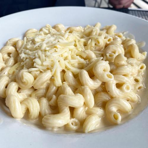 A close-up of a bowl of creamy macaroni and cheese topped with shredded cheese.