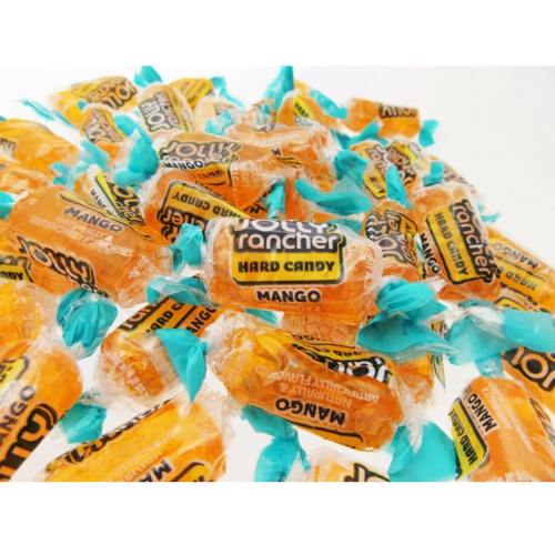 A pile of orange and blue-wrapped mango-flavored hard candies scattered on a white surface.