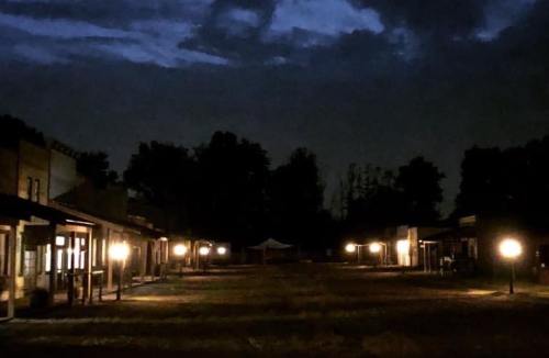 A dimly lit street in a western-style town at night, with buildings and lanterns casting soft light.