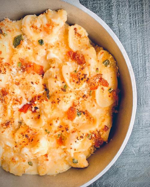 Creamy baked macaroni and cheese with a golden breadcrumb topping in a round dish.