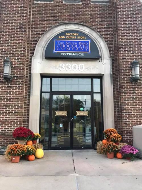 Entrance of the South Bend Chocolate Company, featuring fall decorations with pumpkins and mums.