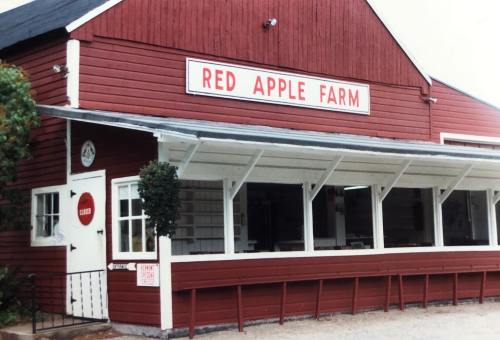 A red barn-style building with a sign reading "Red Apple Farm" and a porch area.