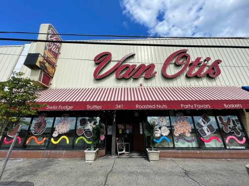 Exterior of Van Otis shop featuring colorful window displays of sweets and treats, with a striped awning above the entrance.