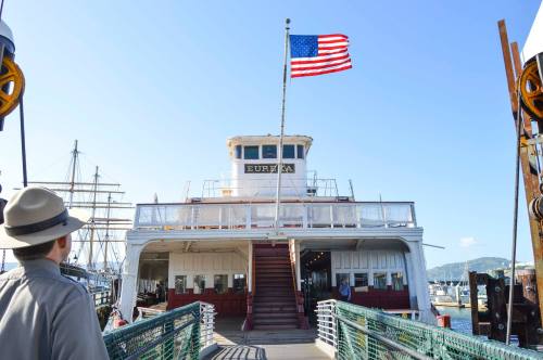 A person stands on a dock, looking at the Eureka boat with an American flag flying above it.