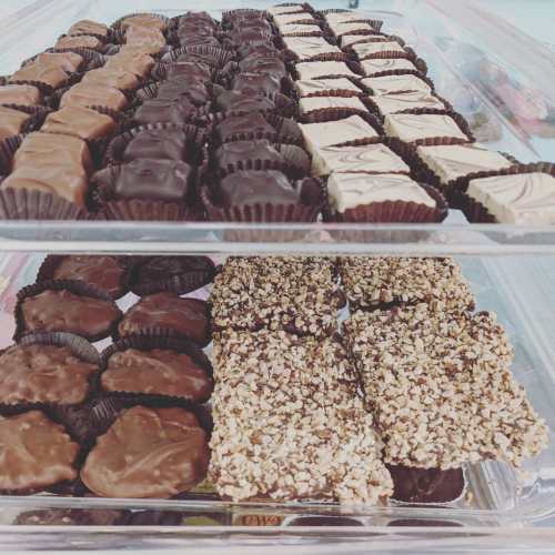 A clear container filled with assorted chocolates, including dark, milk, and nut-covered varieties.