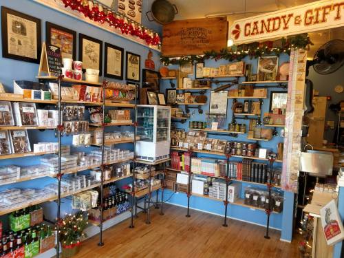 A colorful shop interior filled with shelves of candy, gifts, and various packaged goods, decorated for the holidays.