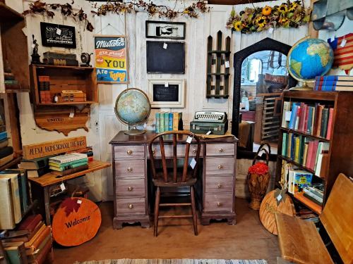 A cozy vintage study with a wooden desk, globe, typewriter, bookshelves, and decorative items in a charming setting.