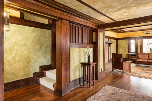 Interior of a cozy room featuring wooden accents, a small staircase, and warm yellow walls.